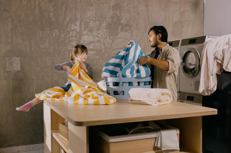 Foto av et barn og en mann som bretter klesvask i OBOS Living Lab.
