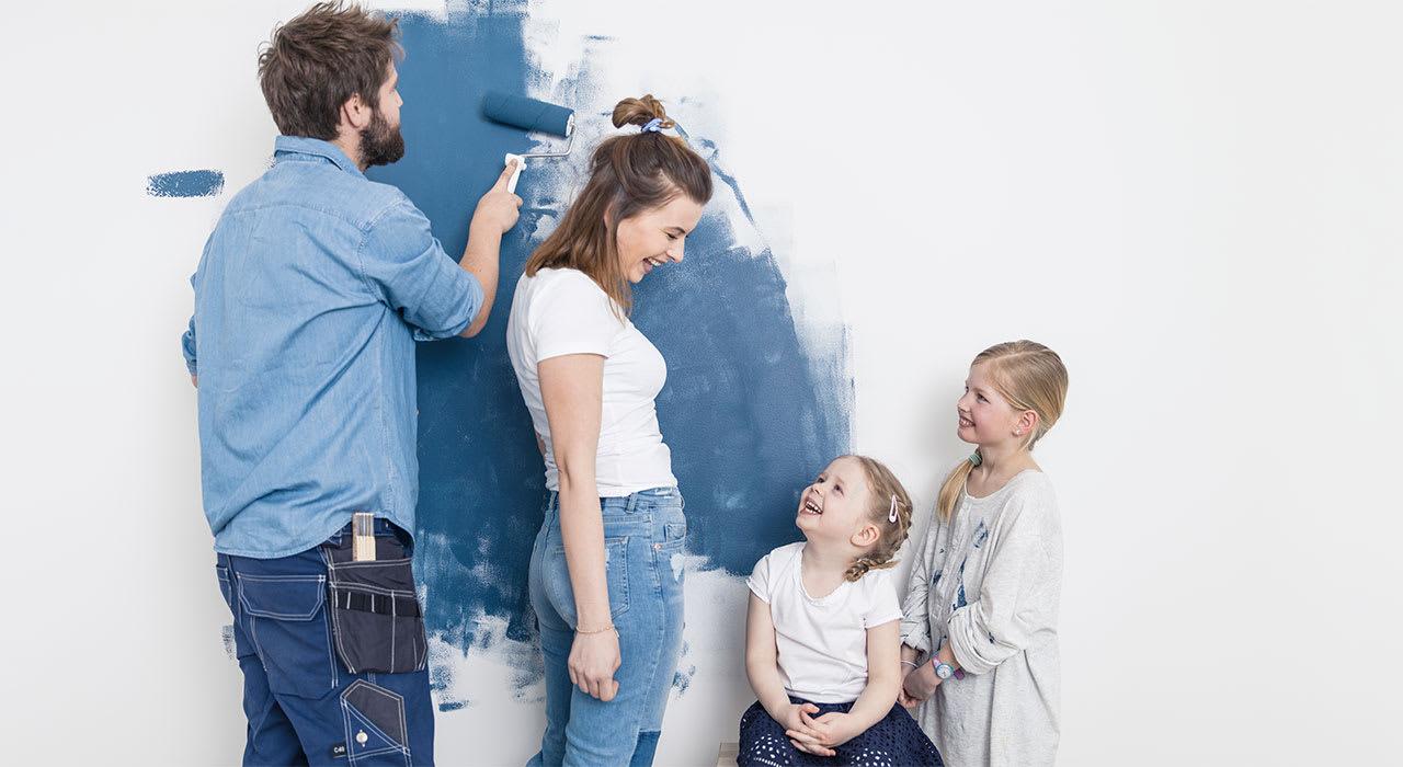 Familie som maler veggen blå.